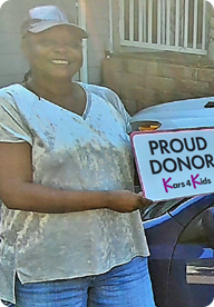 A person holding a sign that says Proud Donor Kars4Kids