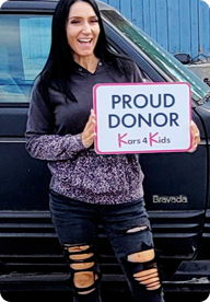 A person holding a sign that says Proud Donor Kars4Kids