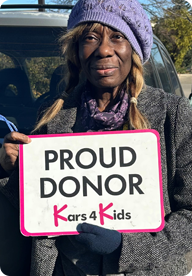 A person holding a sign that says Proud Donor Kars4Kids